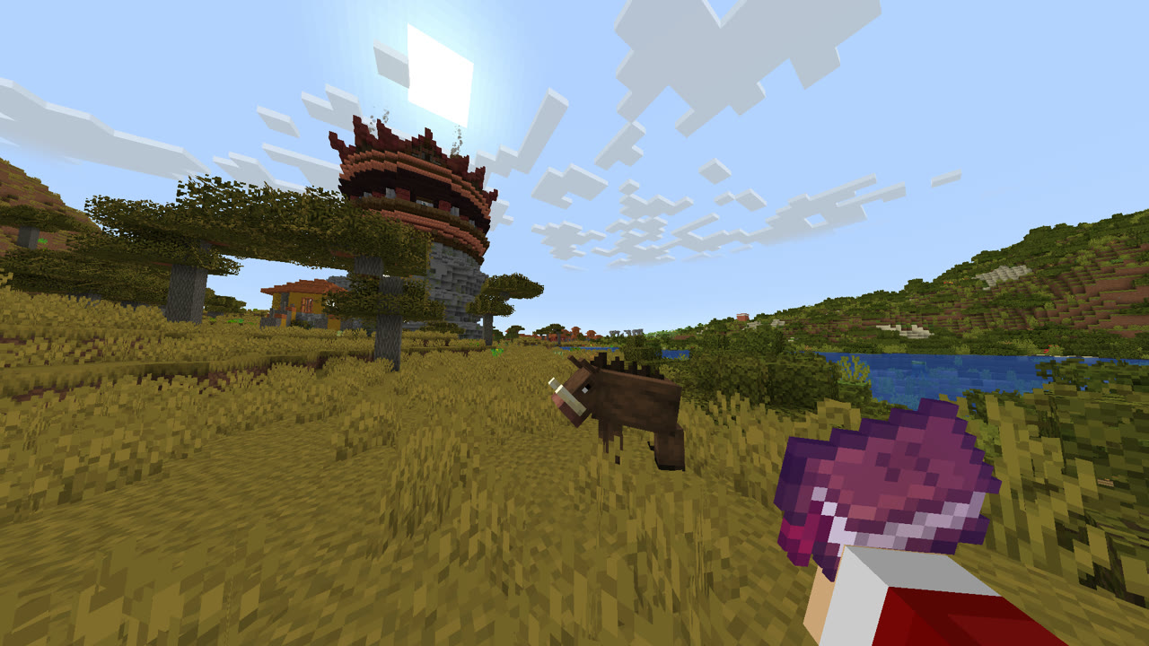 Captura dentro del juego: una sabana dorada con una torre de piedra y madera roja en lo alto de una colina y un animal pastando